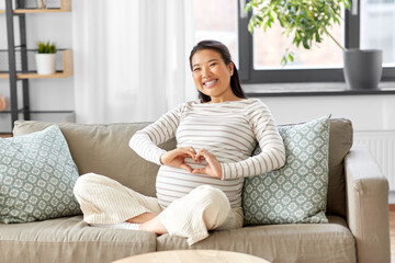 pregnancy, rest, people and expectation concept - happy smiling pregnant asian woman showing hand...