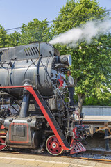 Worker washes a black retro steam locomotive on the railway platform of the Rizhsky station. Moscow, Russia