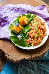 Vegan scrambled eggs dish with green and corn colorful tasty flat lay top view violets flower decoration food styling inspiration plant based food