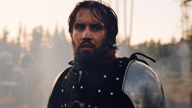 Handsome Medieval Knight King on Battlefield, Looking at Camera. Portrait of Mighty Warrior Soldier Contemplating Victory. War, Invasion, Conquest. Dramatic Scene in Cinematic Historic Reenactment