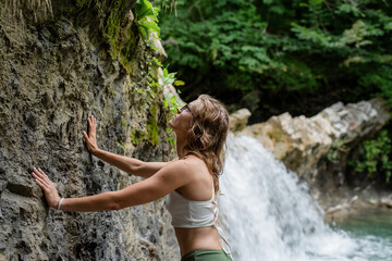 Young sexy woman in swimsuit enjoing the waterfall