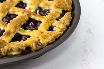 American cherry pie in baking dish on a white background