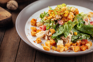 Russian malibu salad with croutons and ham on wooden background