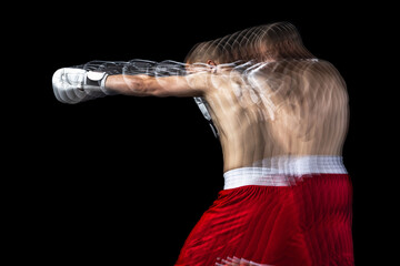 Young professional male boxer in red shorts training, exercising over black background. Stroboscope