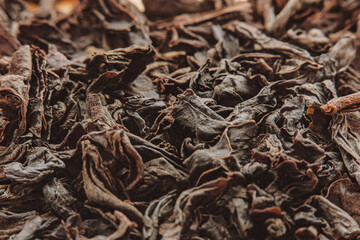 Close-up of a pile of dry black tea leaves in soft focus at high magnification. Dry plants for the preparation of a traditional drink.