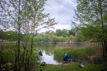 Fishing as a hobby. A woman fishing with a fishing rod on the shore of a pond, river or lake, will spend her free time.