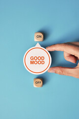 A switch with the inscription: good mood and on and off icons. A person chooses the positive in life