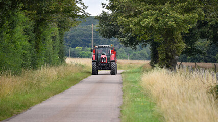 Farmer driving a red tractor a on road in the countryside.
