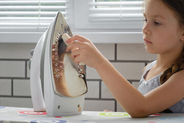 The girl child cleans the sole of the iron with a special cleaning pencil, cleaning the iron from carbon deposits, close-up