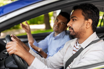 driver courses and people concept - driving school instructor talking to sad indian man failed exam in car