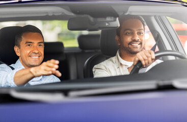 driver courses and people concept - happy smiling car driving school instructor teaching young man to drive