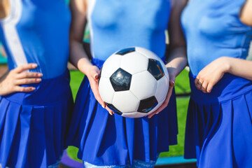 Female group of cheerleader in action, wearing white blue uniform with audience in the background performing and supporting during football game match