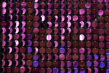 shiny texture of the background, a set of round purple sequins sewn on the fabric like fish scales