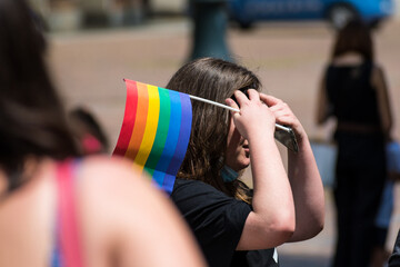 Group of young people in the pride parade on the city street with gay rainbow flag, supporting gay...