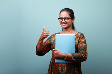 Smiling woman of Indian origin holding a file and shows thumbs up sign