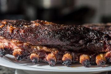 Smoked beef rib placed on a white plate with copy space and slightly dark background