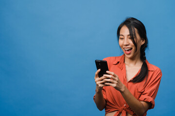 Young Asia lady using phone with positive expression, smiles broadly, dressed in casual clothing...
