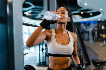 Beautiful young Asia lady exercise drinking water after fat burning workout in fitness class....