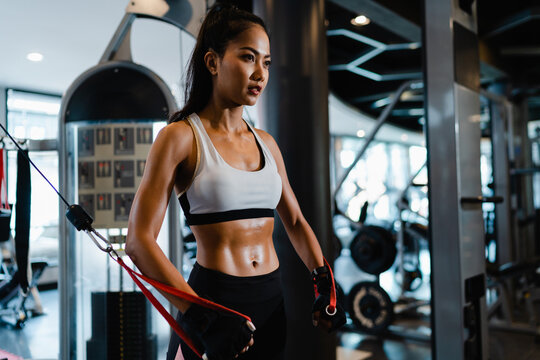Young Asia lady exercise doing exercise-machine Cable Crossover fat burning workout in fitness class. Athlete with six pack, Sportswoman recreational activity, functional training, healthy lifestyle.