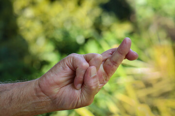 Mano umana con dita incrociate su sfondo naturale.