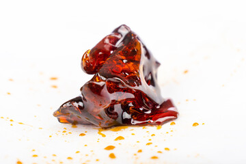 a piece of dark amber cannabis wax concentrate close up on white paper
