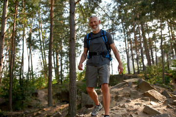 Happy middle aged caucasian man trekking in forest