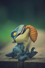 Closeup shot of a mini blue dinosaur funny toy with food in the mouth