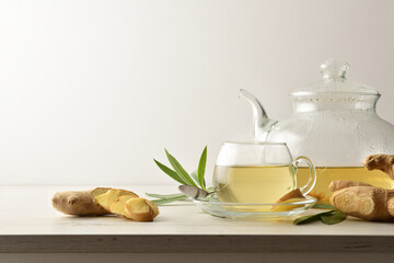 Cup with ginger drink on table with teapot isolated background