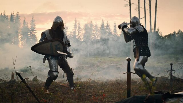Epic Battlefield: Two Armored Medieval Knights Fighting with Swords. Dark Ages Army Warfare. Action Battle of Armored Warrior Soldiers, Killing Enemy. Cinematic Historical Reenactment. Slow Motion