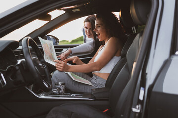 two girls travel the roads in a car, look at the map. Vacation concept