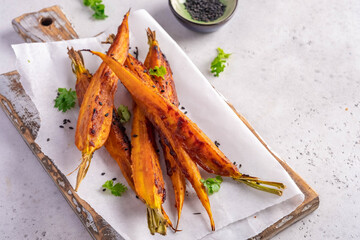 Glazed and roasted young red carrots on a piece of baking paper, white background