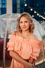 portrait of an attractive woman in a pink dress in a rooftop cafe