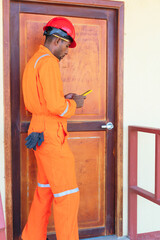 African professional technician is resting and using cell phone.