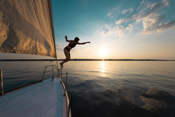 Girl jumping into the water from a yacht