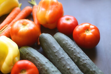 Zucchini, tomatoes, peppers, carrots and cucumbers on dark background. Selective focus.