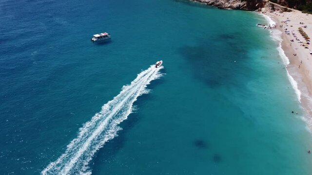 Drone view of a boat the blue clear waters. Top view of a white boat sailing to the blue sea. Large speed boat moving at high speed. Travel - image