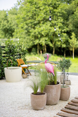 Beautiful backyard in natural boho style with garden furniture, greens and pink flamingo