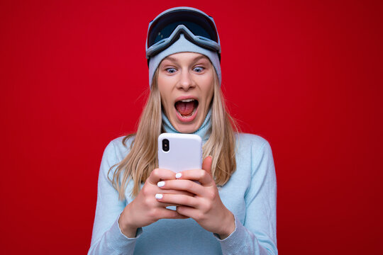 Portrait of a young woman in a sweater and ski goggles with a phone