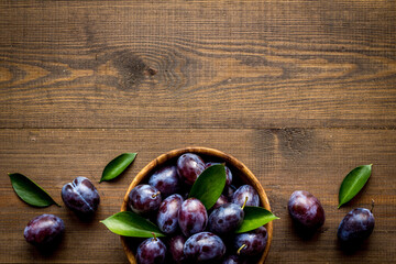Purple plums with leaves top view. Food fruits background