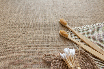 Fototapeta na wymiar Natural bathroom tools, sustainable zero waste and lifestyle concept. Wooden toothbrushes, bamboo swabs and jute washcloth on fabric background with copy space, mockup