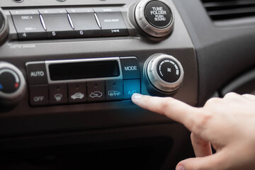 The hand adjusts the air conditioner in the car. Close up