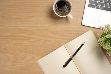 Desk office with laptop, blank notepad, coffee cup and pen on wood table. Flat lay top view copy spce.