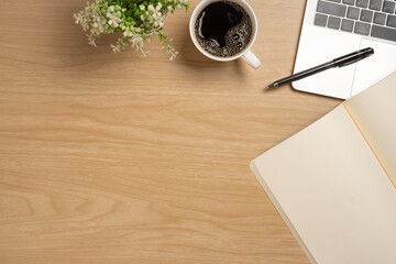 Desk office with laptop, blank notepad, coffee cup and pen on wood table. Flat lay top view copy spce.