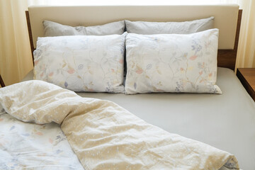 Top view shot of an unmade bed in a hotel room with ironed grey sheets, white blanket and two...