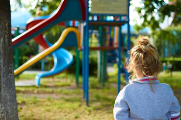 Cute little girl looking with his back turned on the playground in park 