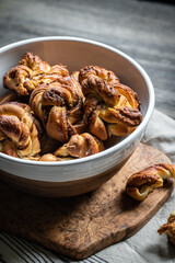 Bowl with freshly baked cinnamon yeast knot buns on dark background .