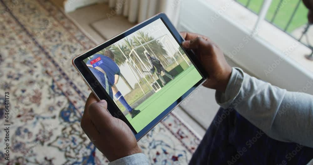 Wall mural Composite of man sitting at home, watching hockey match on tablet