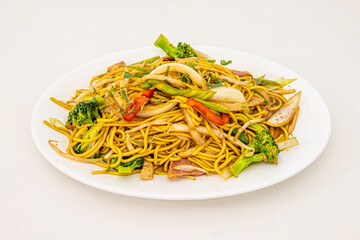 Peruvian recipe of sautéed noodles with beef tenderloin, onion and red and green peppers, some carrot and soy sauce on a white tray
