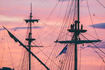 sailors take a selfie on the mast of a sailing ship at sunset