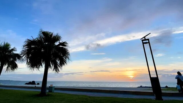 CHTAN-CHO, OKINAWA, JAPAN - JUNE 2021 : View of Araha beach (Ocean or sea) in sunset time. Wide view time lapse tracking shot, dusk to night. Holiday, vacation and resort concept shot.